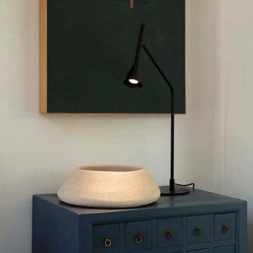 Lampe à poser noire sur un meuble ciblant un pot de rangement 
