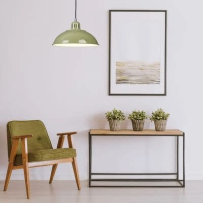 Suspension verte au-dessus d'un fauteuil vert et bois et à côté d'un meuble d'appoint avec fleur et tableau au-dessus