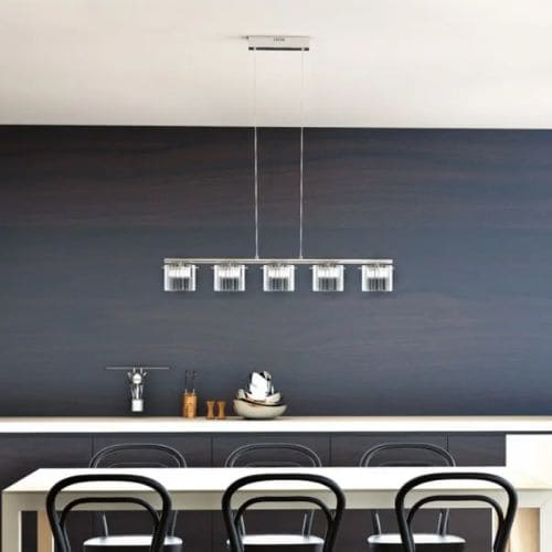 Luminaire cuisine moderne suspendu au-dessus d’un plan de travail de cuisine, avec cinq suspensions lumineuses et un éclairage LED le long du bar.