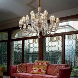 Suspension chandelier élégante en cristal au-dessus d’un canapé rose, dans un salon lumineux avec vitraux et décorations. Comment choisir un lustre de salon.