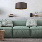 Suspension moderne sombre au-dessus d’un canapé vert d’intérieur, livres et plantes sur l’étagère, ambiance cosy dans une chambre/salon. luminaire chambre à coucher adulte.