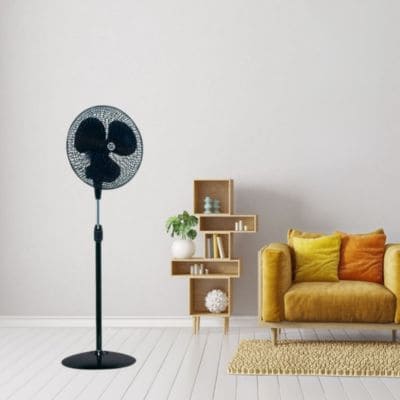 Ventilateur bébé nuit : ventilateur debout dans un salon minimaliste, près d’un canapé jaune et d’une étagère décorative.