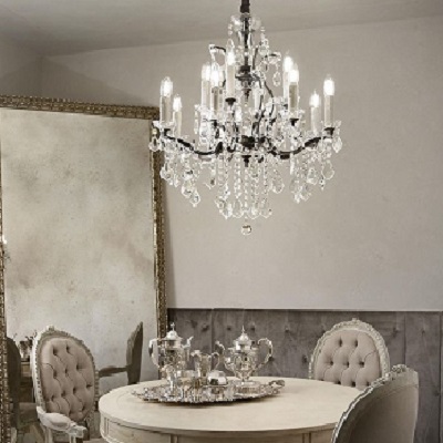 Chandelier avec cristaux suspendu au plafond au-dessus d'une table ronde et d'un miroir ornate.
