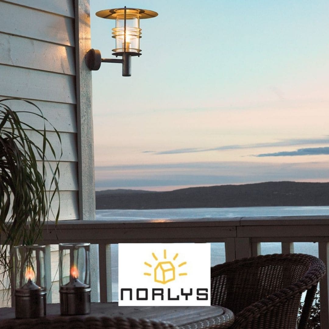 Lampe d’extérieur murale en inox fixée au côté d’une terrasse avec une vue sur la mer au coucher du soleil.
