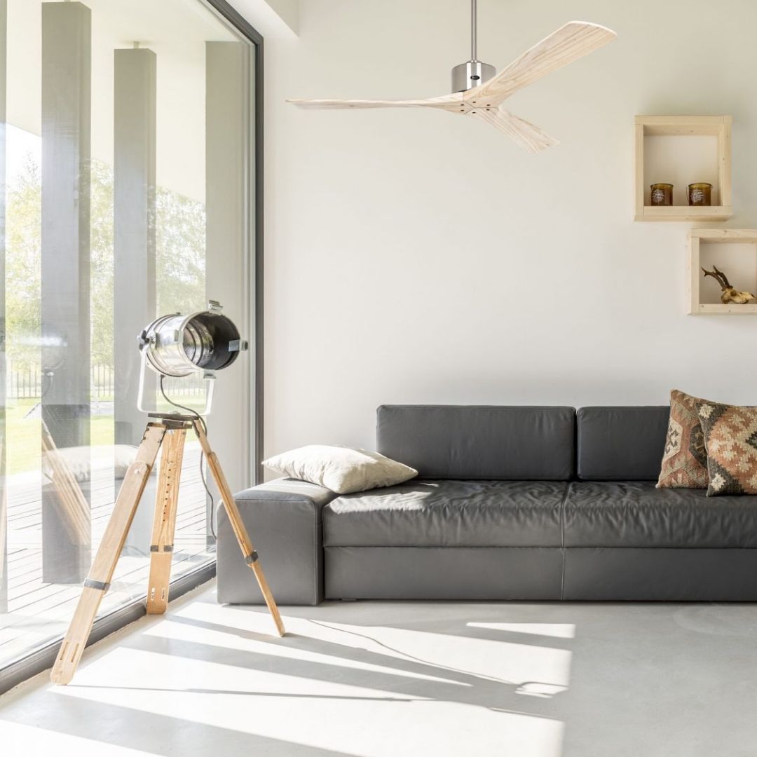 Lumière naturelle dans un salon moderne avec canapé gris et lampe guidée par une source lumineuse près d’une porte-fenêtre.