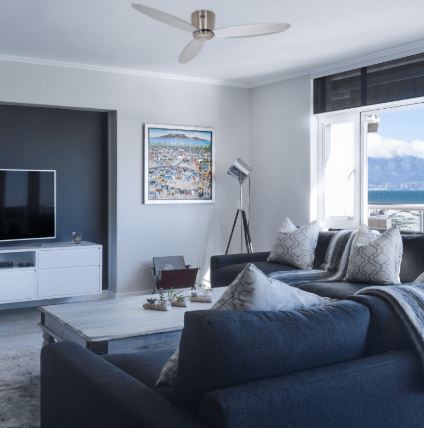 Vue d’un salon lumineux avec un ventilateur de plafond moderne au centre.