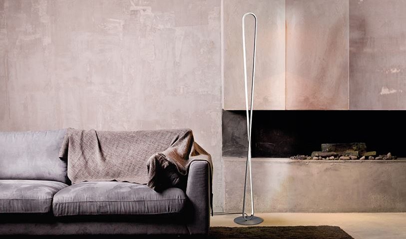 Lampadaire moderne près d’un canapé dans un salon, avec foyer et murs gris.